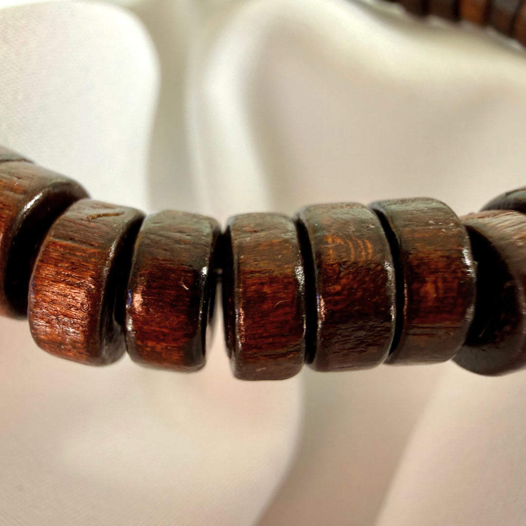 Close-up of a brown wooden bracelet made entirely of flat wooden beads.