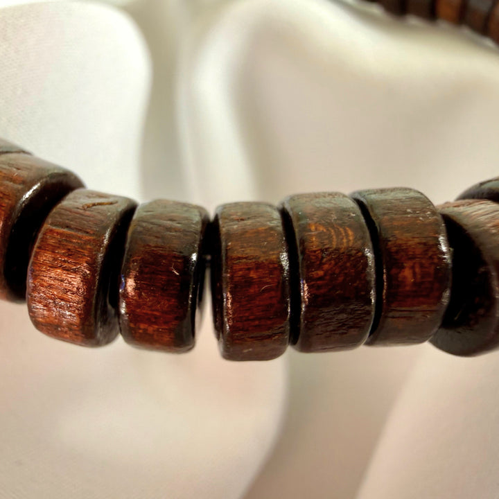 Close-up of a brown wooden bracelet made entirely of flat wooden beads.