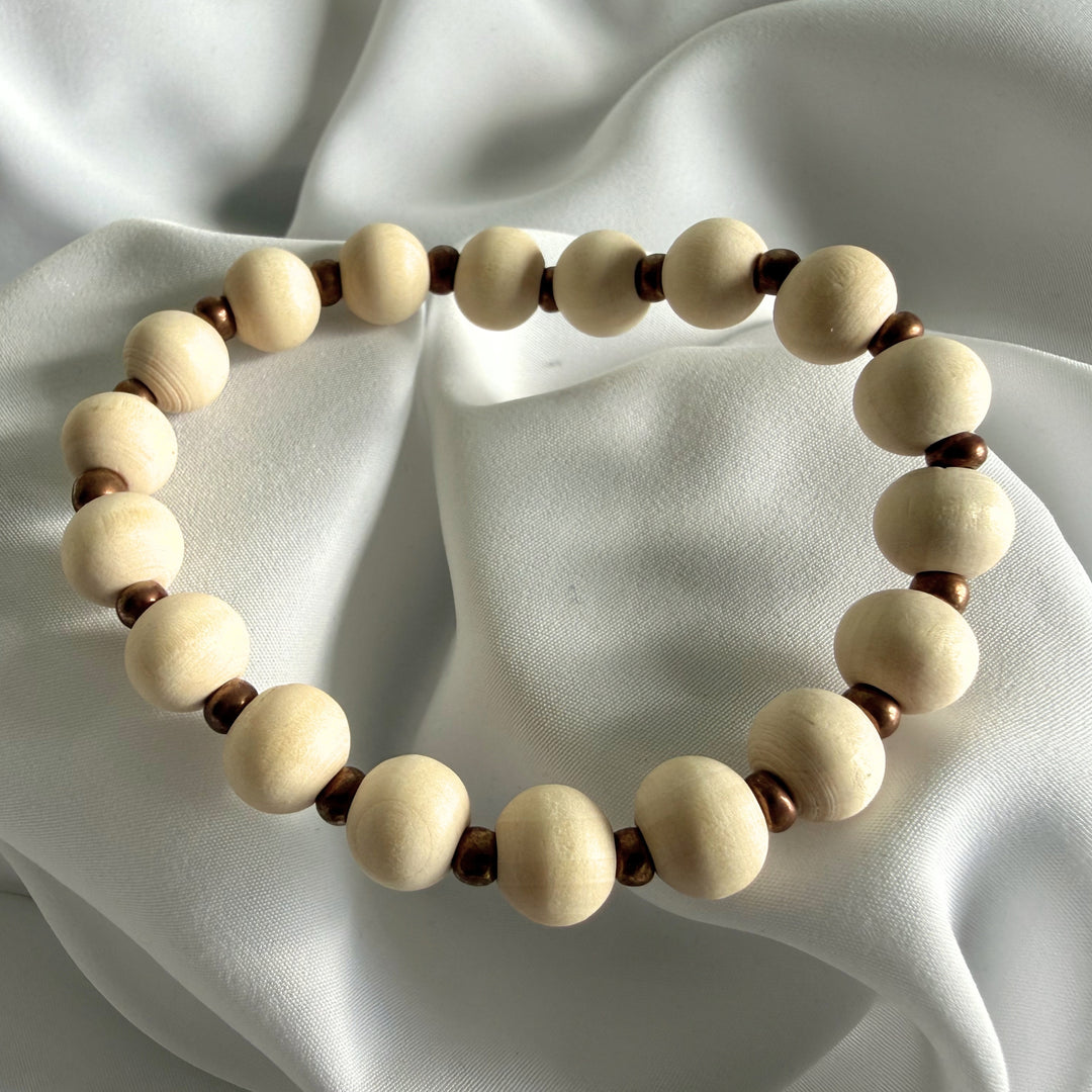 Full view of a handcrafted bracelet made with ivory wood beads and golden seed bead accents.