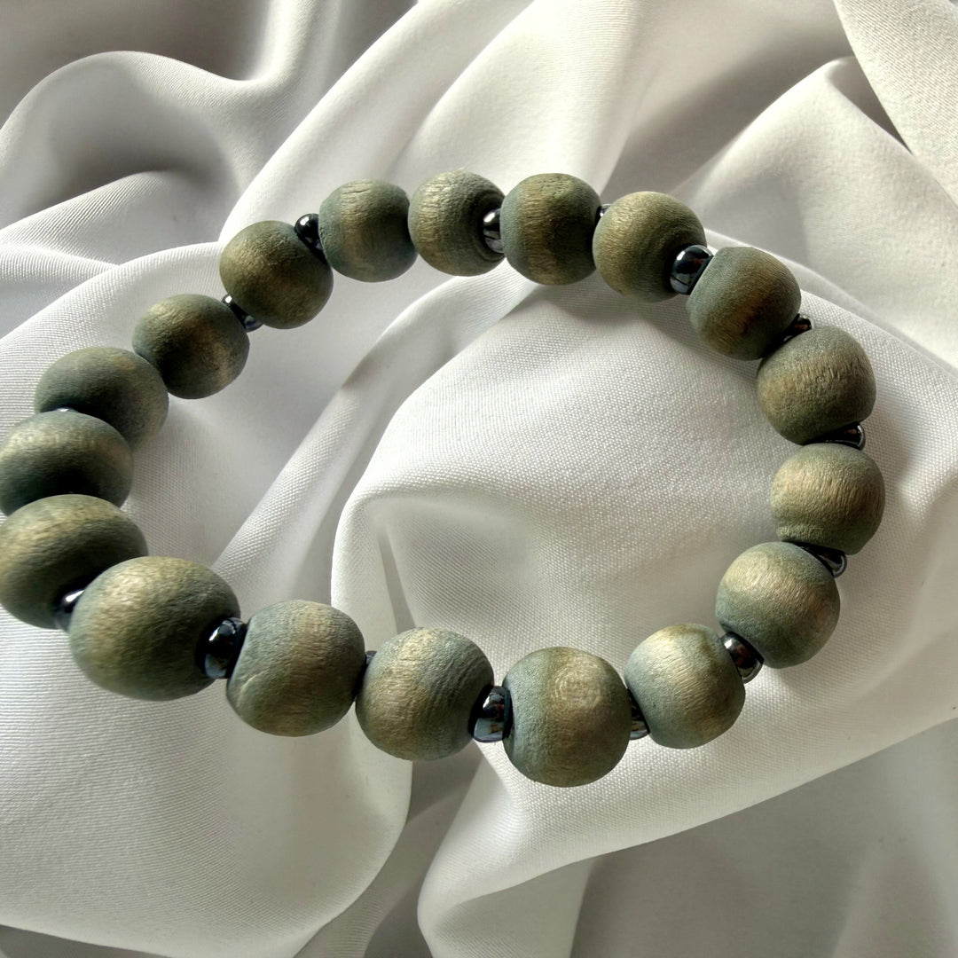 Full view of a handcrafted bracelet made with grey wood beads and silver-coloured seed beads on elastic cord.