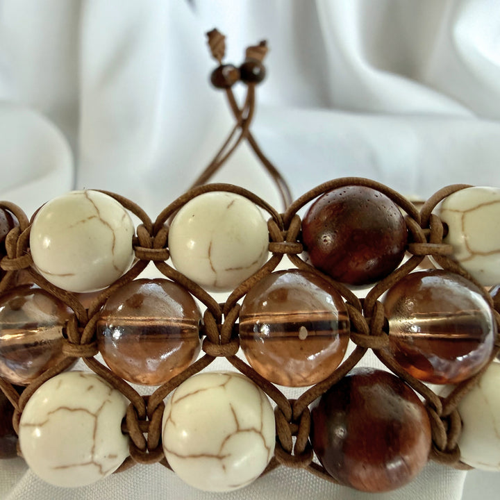 Close-up of detailed macramé knotting with howlite, wood, and glass beads on a handmade bracelet.