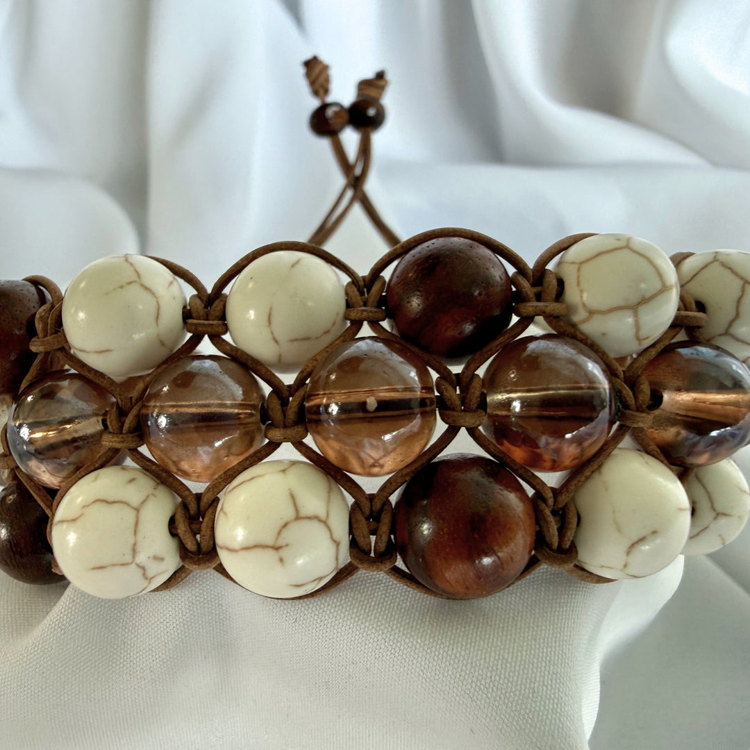 Front view of a handcrafted howlite macramé bracelet with wood and glass beads in brown and white tones.