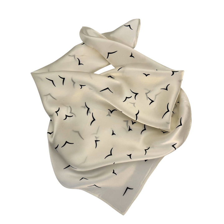 Ivory silk scarf neatly folded showing the scattered V bird pattern.