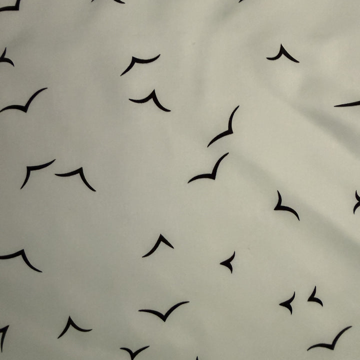 Close-up of black V-shaped bird motifs on ivory silk fabric.