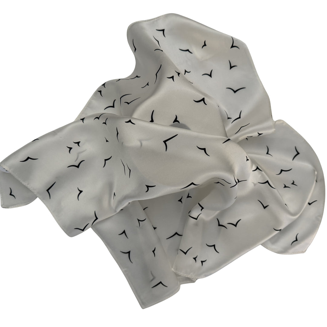 Ivory silk scarf loosely spread to display the full V bird design.