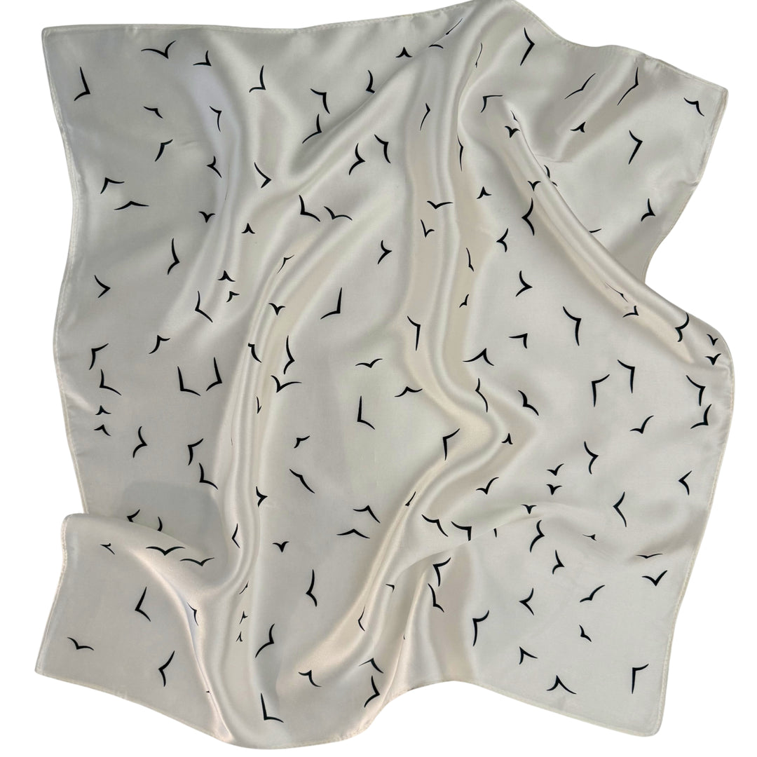 Ivory silk scarf softly laid out in a relaxed arrangement.