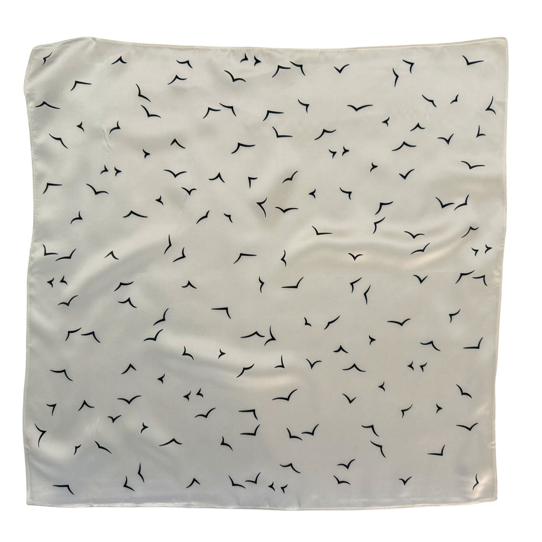 Ivory silk scarf with black V-shaped bird pattern shown in full top view.