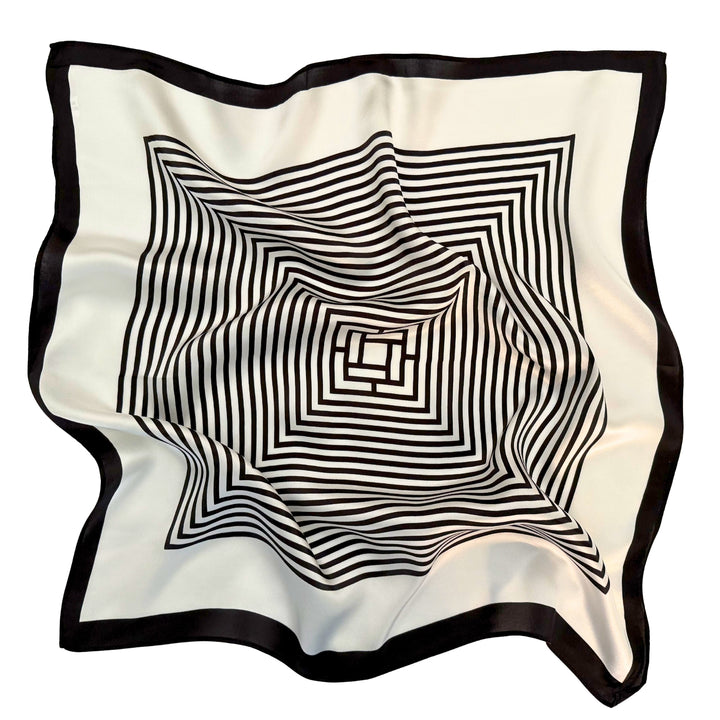 Mulberry silk scarf laid flat in a relaxed arrangement showing the full black and ivory geometric labyrinth pattern and border.