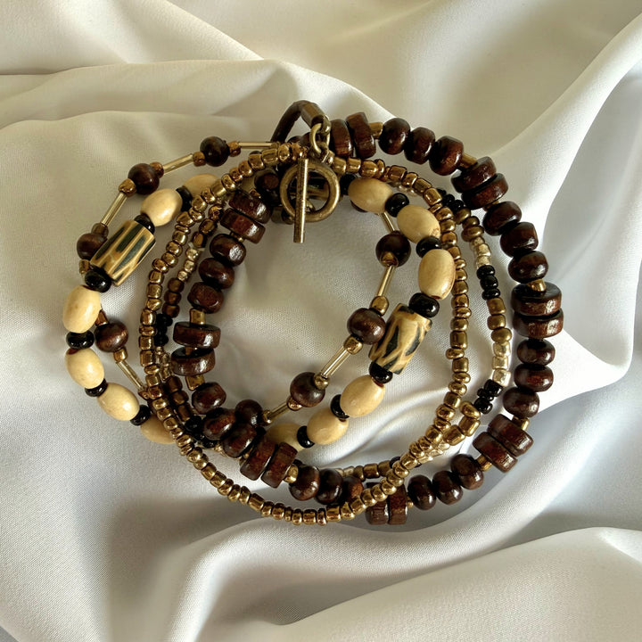 Five-strand beaded bracelet stacked together showing layered textures of wood, glass, and polymer clay beads.