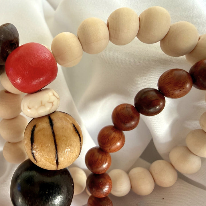 Close-up of three layered bracelets made with wood and howlite beads in warm earthy colours.