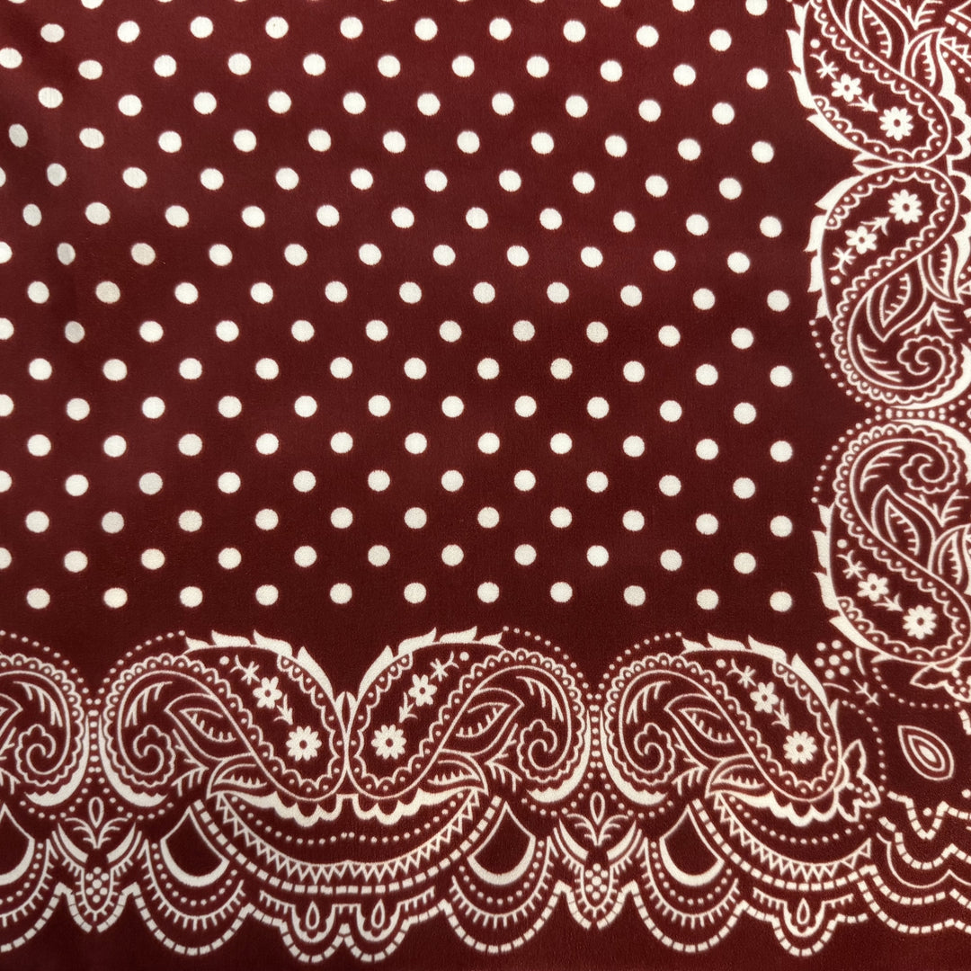 Close-up of paisley border and white dot pattern on maroon silk fabric.
