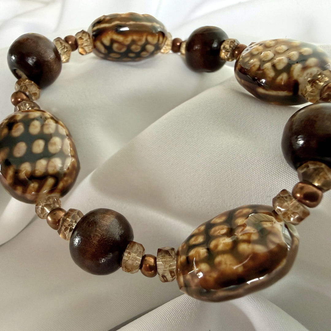 Angled view of a mixed bead bracelet featuring patterned ceramic and natural wood beads.