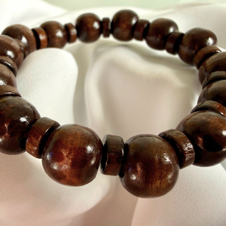 Close-up of a brown wooden bracelet featuring a mix of round and flat beads.