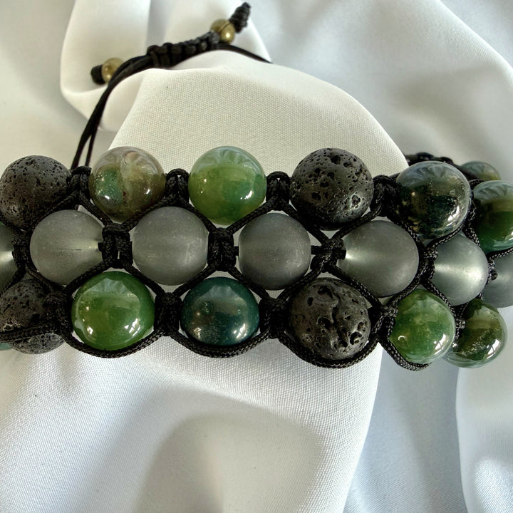 Angled close-up front view of a handcrafted moss agate macramé bracelet showing green natural stone patterns and textured beads.