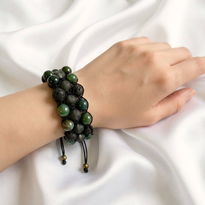 Handcrafted moss agate macramé bracelet worn on a woman’s wrist showing earthy green and black tones.