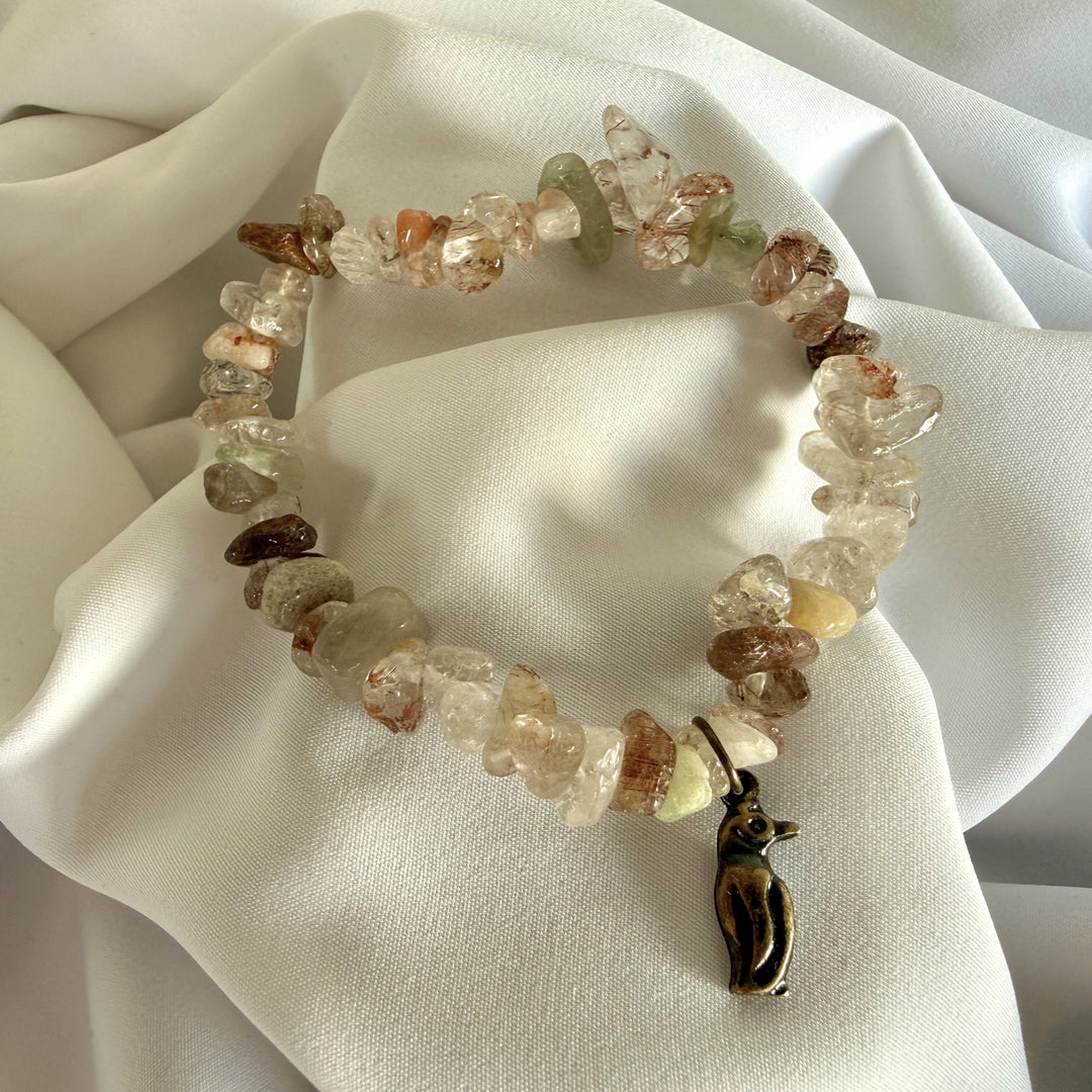 Full view of a handcrafted mother of pearl chip bead bracelet with a small penguin charm.