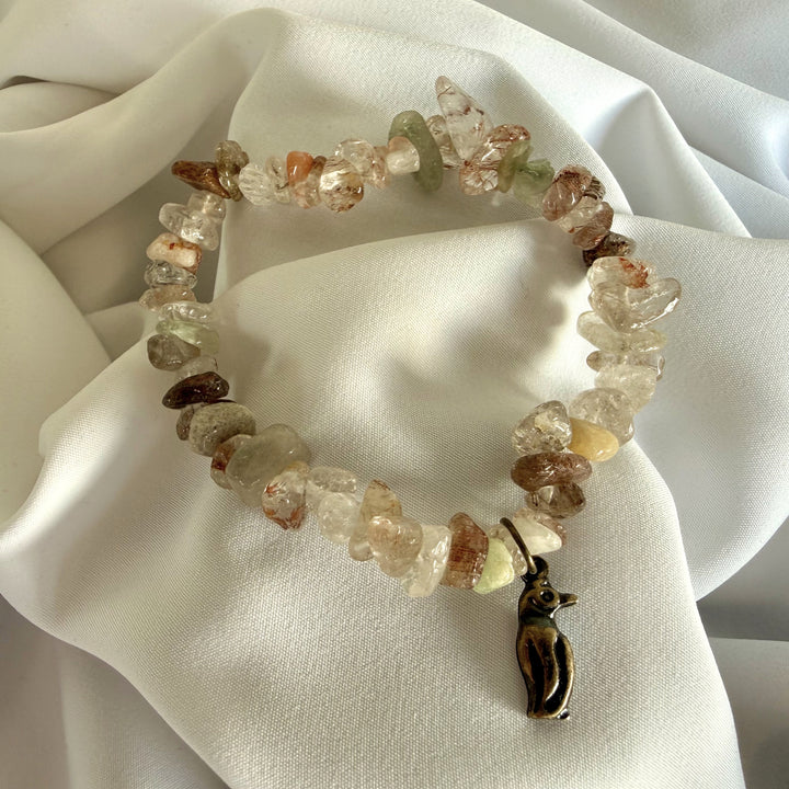 Full view of a handcrafted mother of pearl chip bead bracelet with a small penguin charm.