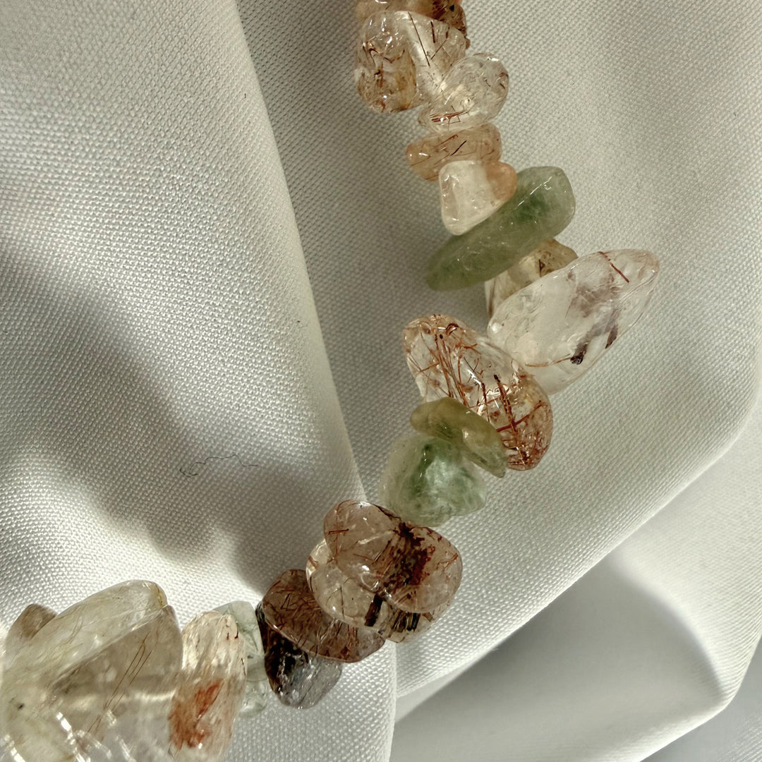 Close-up of iridescent mother of pearl chip beads and penguin charm on a handmade bracelet.