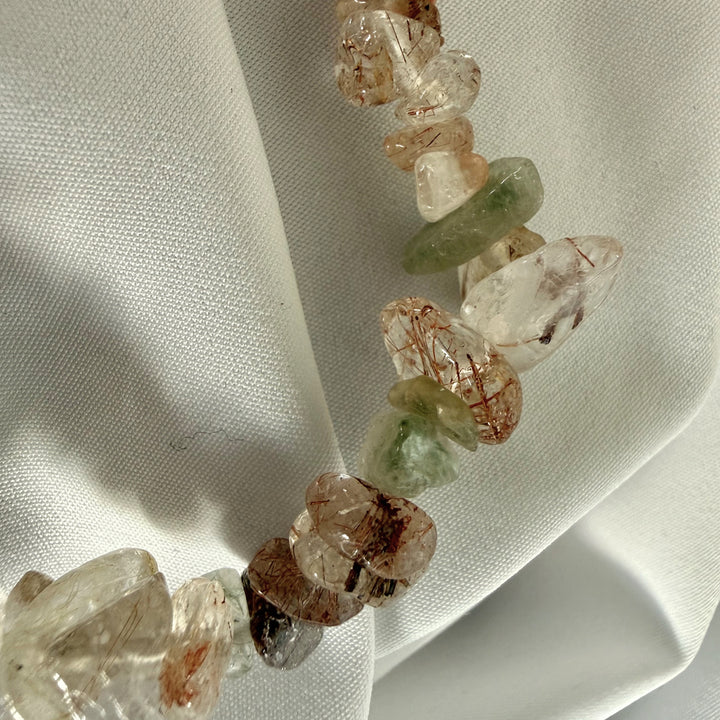 Close-up of iridescent mother of pearl chip beads and penguin charm on a handmade bracelet.