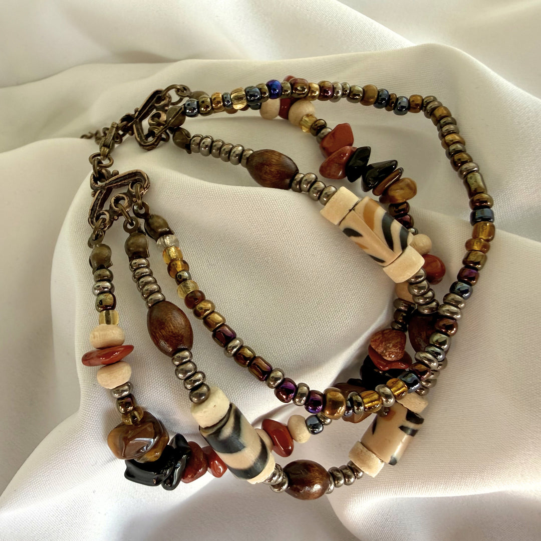 Full view of a handcrafted multi-strand African beaded bracelet with chip stones, wood, coco, and patterned polymer clay beads.