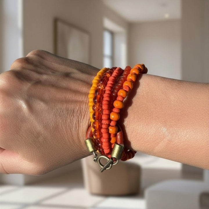 Handcrafted multi-strand beaded bracelet with wood and glass beads worn on a wrist, showing warm earthy tones and layered structure.