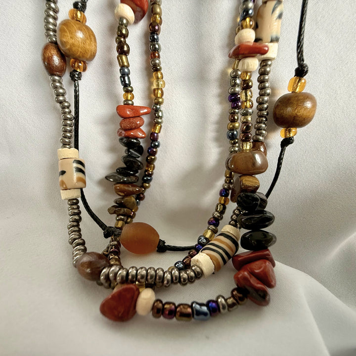 Close-up bottom view of a handcrafted multi-strand necklace showing layered bead strands and natural material variation.