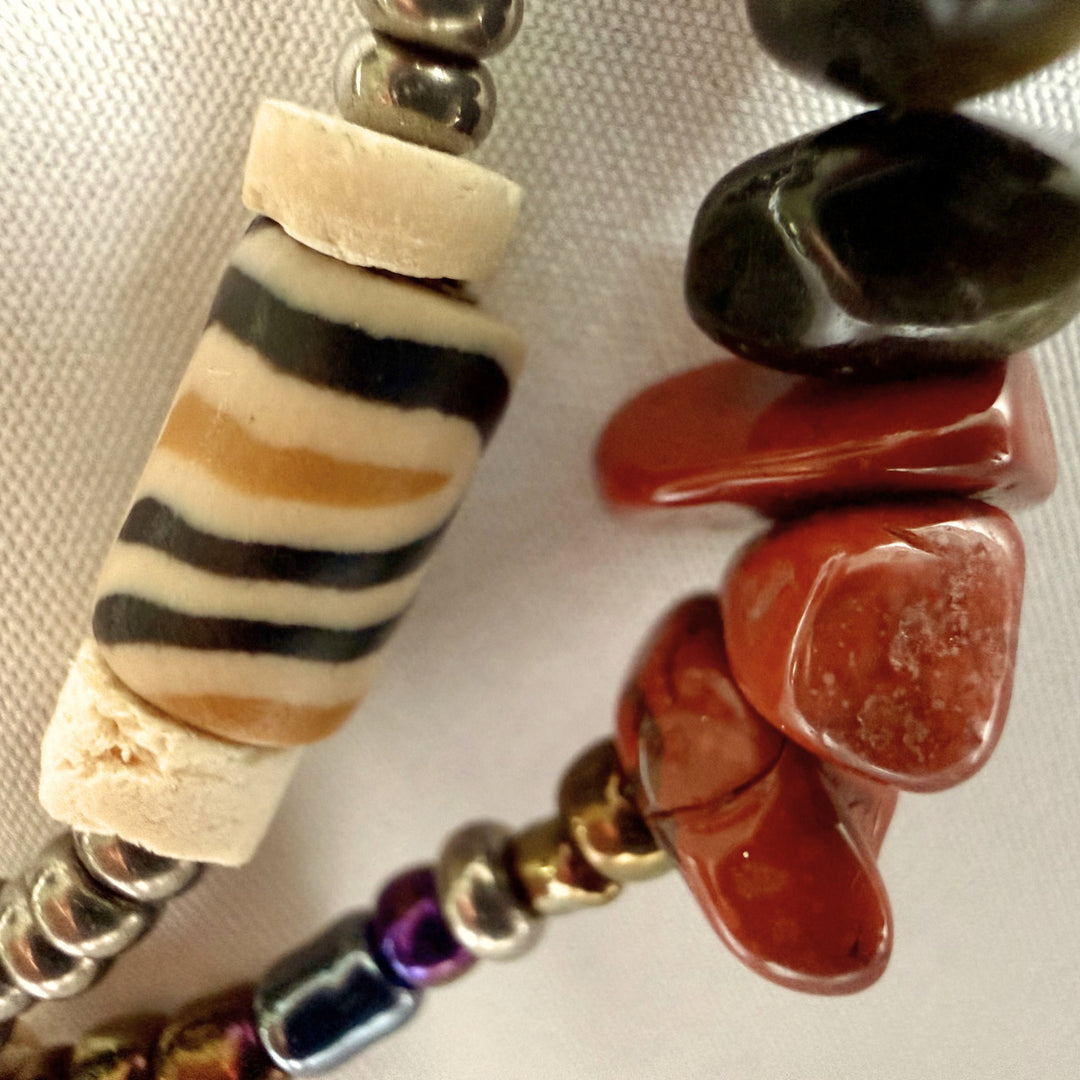Close-up of mixed semi-precious chip beads, polymer clay beads, African print beads, and seed beads in a handcrafted necklace.