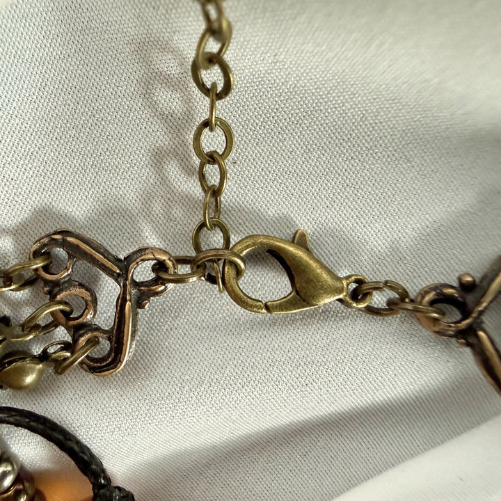 Close-up of adjustable clasp and antique brass chain detail on a handcrafted multi-strand beaded necklace.