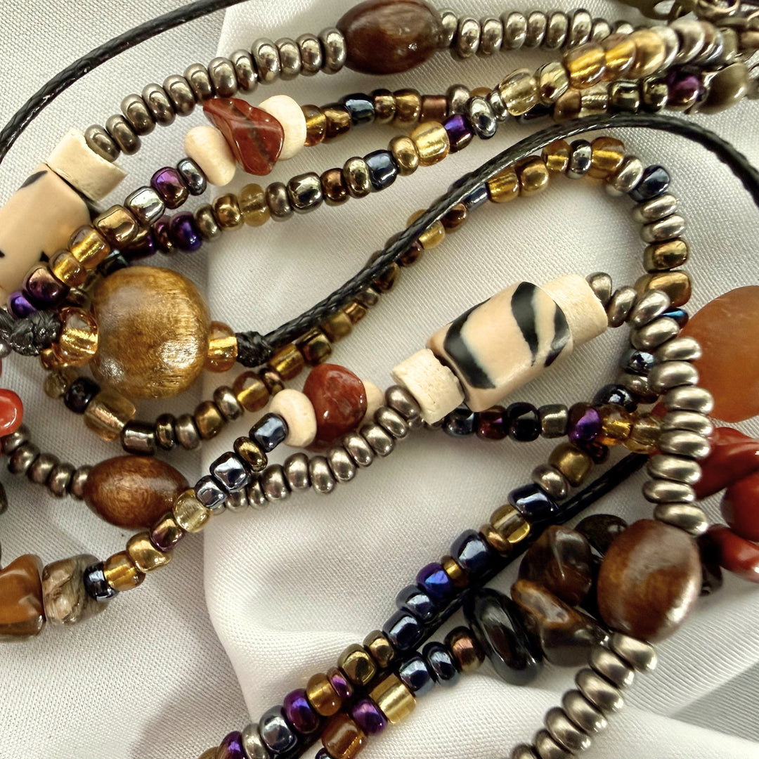 Close-up of a handcrafted three-strand beaded necklace with layered strands showing mixed textures and natural earthy colours.