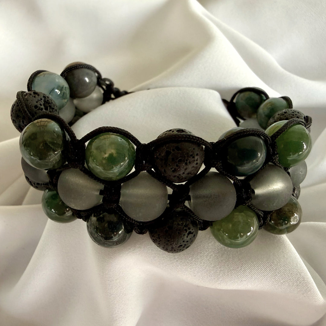 Front view of a moss agate macramé bracelet with green natural stone patterns and black beads.