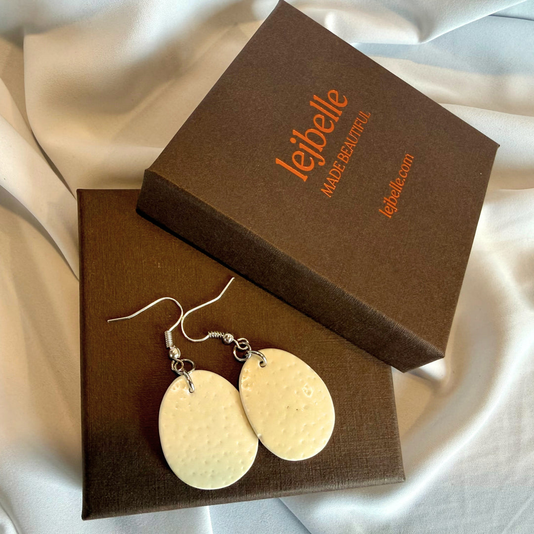 Handcrafted oval ostrich eggshell drop earrings displayed side by side in a branded gift box.