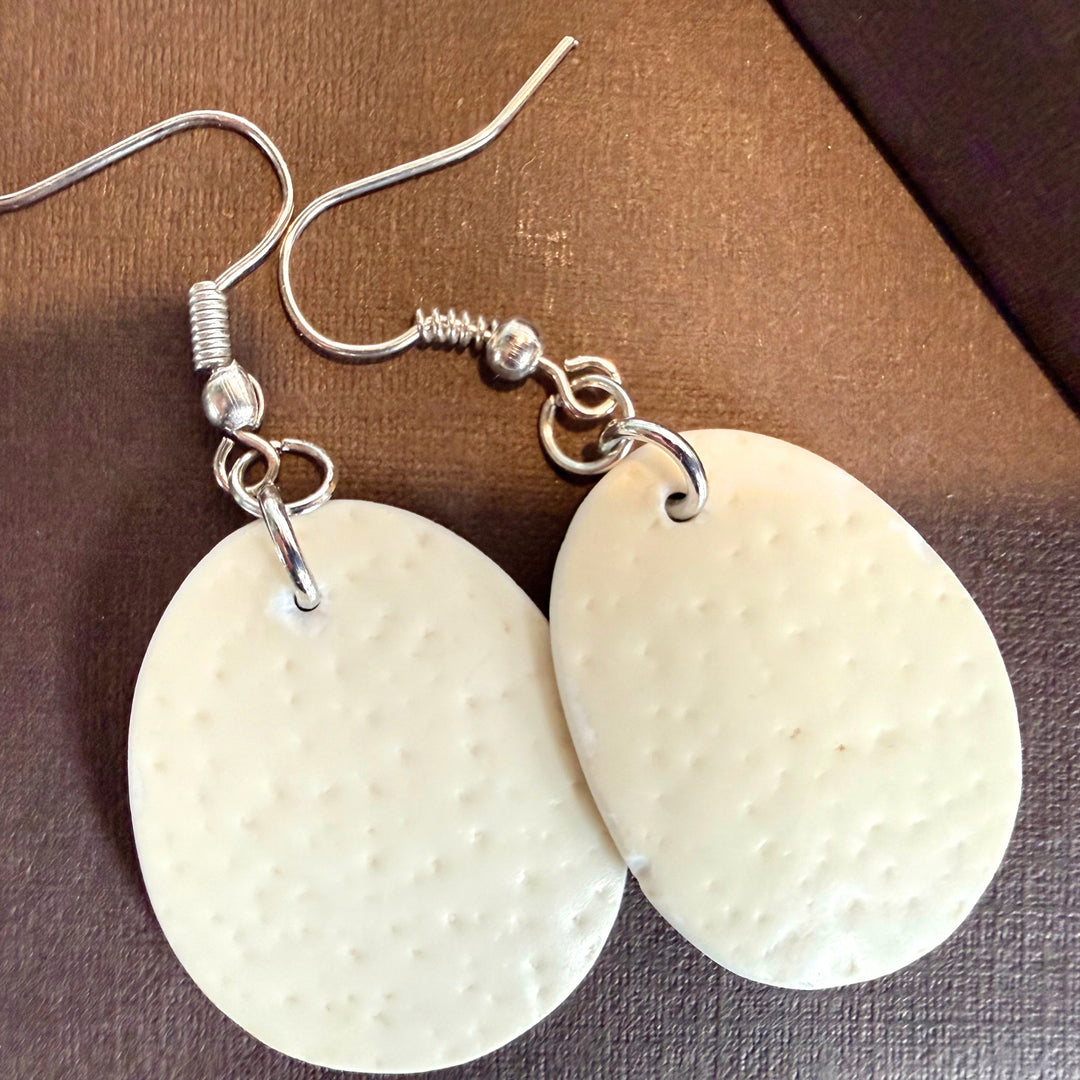 Close-up of handcrafted oval ivory ostrich eggshell drop earrings presented in a gift box with silver-tone hooks.