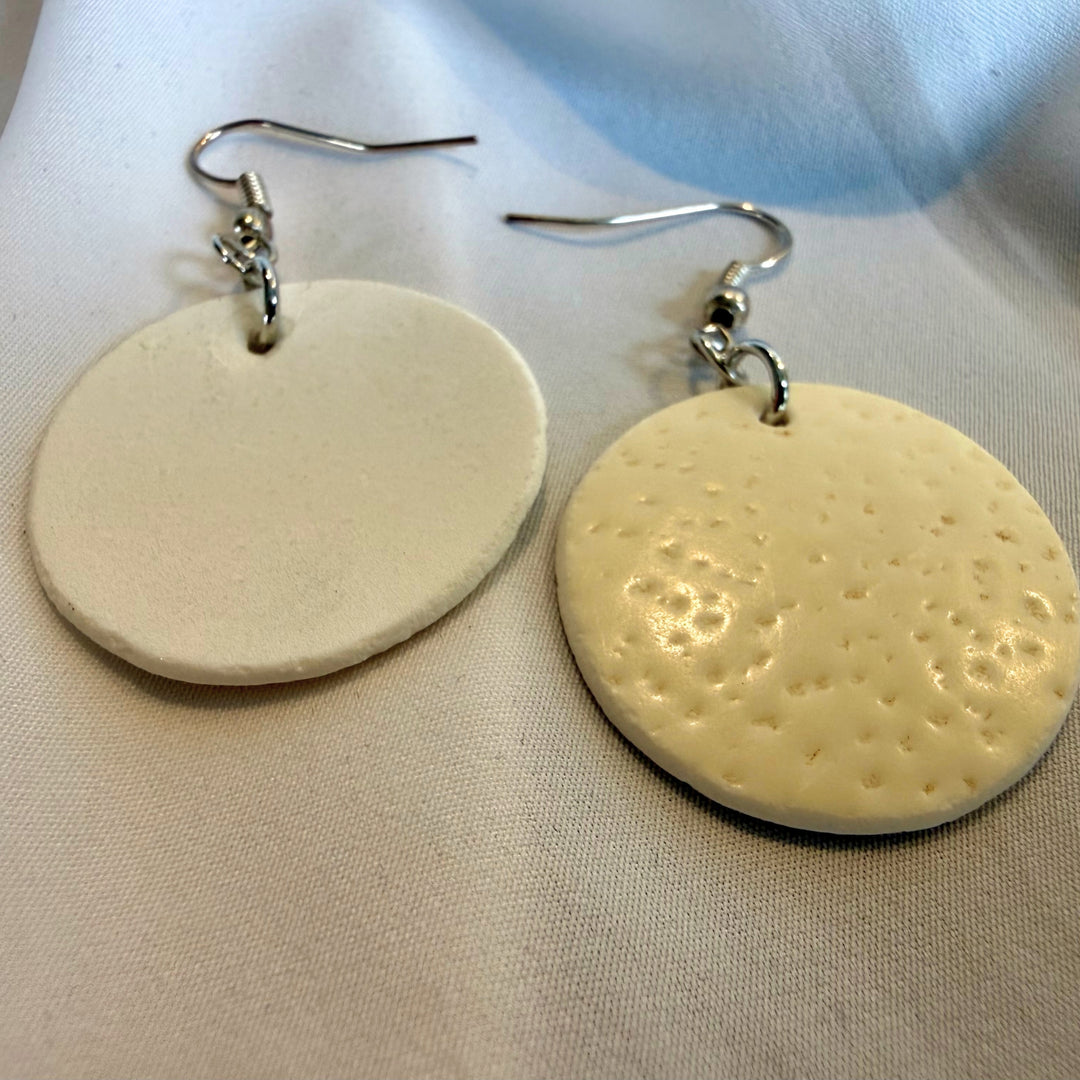 Handcrafted round ostrich eggshell earrings shown with one earring flipped to reveal the back and natural texture variation.