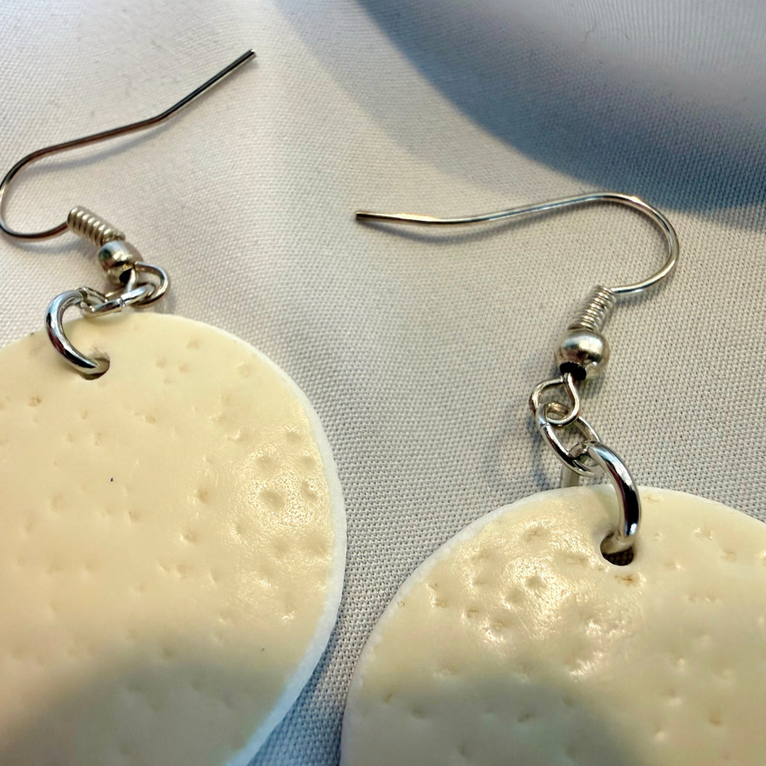 Close-up of round ostrich eggshell drop earrings highlighting silver-tone hooks and metal components with natural ivory beads.