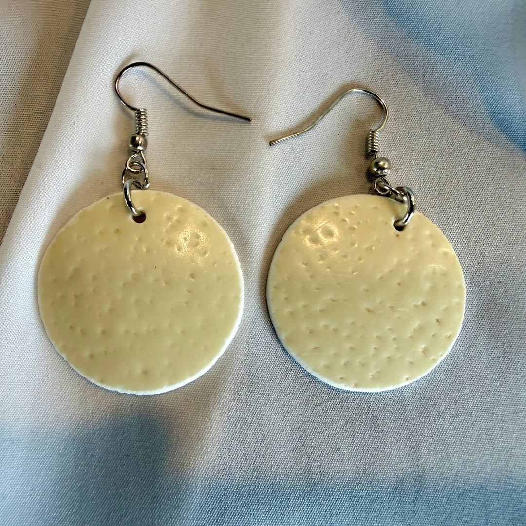 Full view of handcrafted round ostrich eggshell drop earrings in ivory tones with silver-tone hooks.