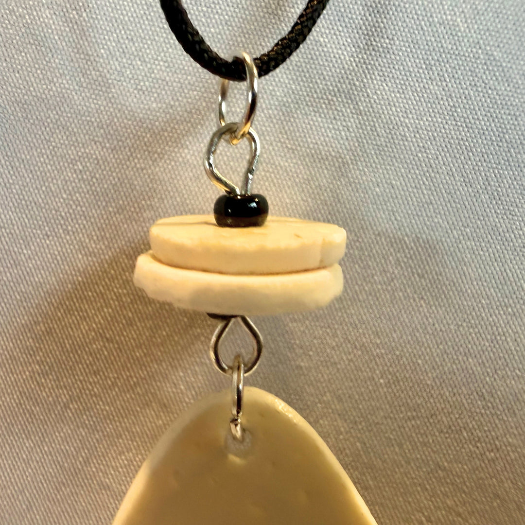 Extreme close-up of natural ostrich eggshell texture and surface detail on a handcrafted pendant necklace.