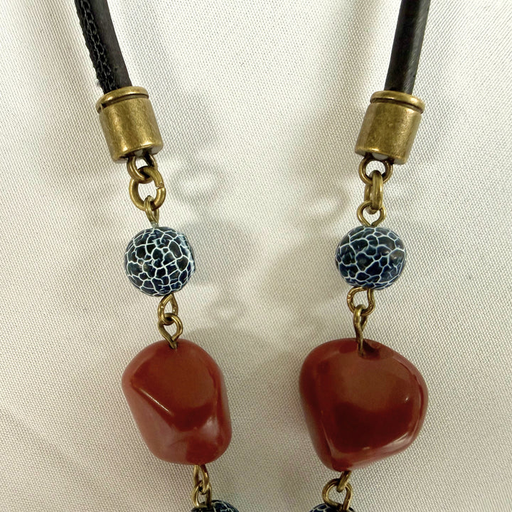 Close-up of red jasper stones used in a handcrafted pendant necklace with black wood and crackle agate.