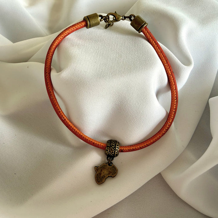 Full view of a handcrafted red cork bracelet featuring an antique brass Africa charm and stainless steel clasp.