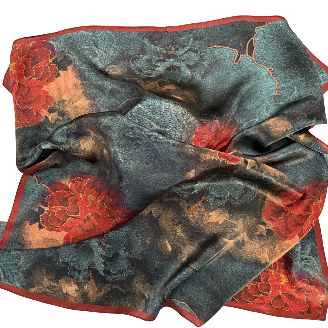 Red and blue floral silk scarf loosely spread to show full floral artwork and red border.