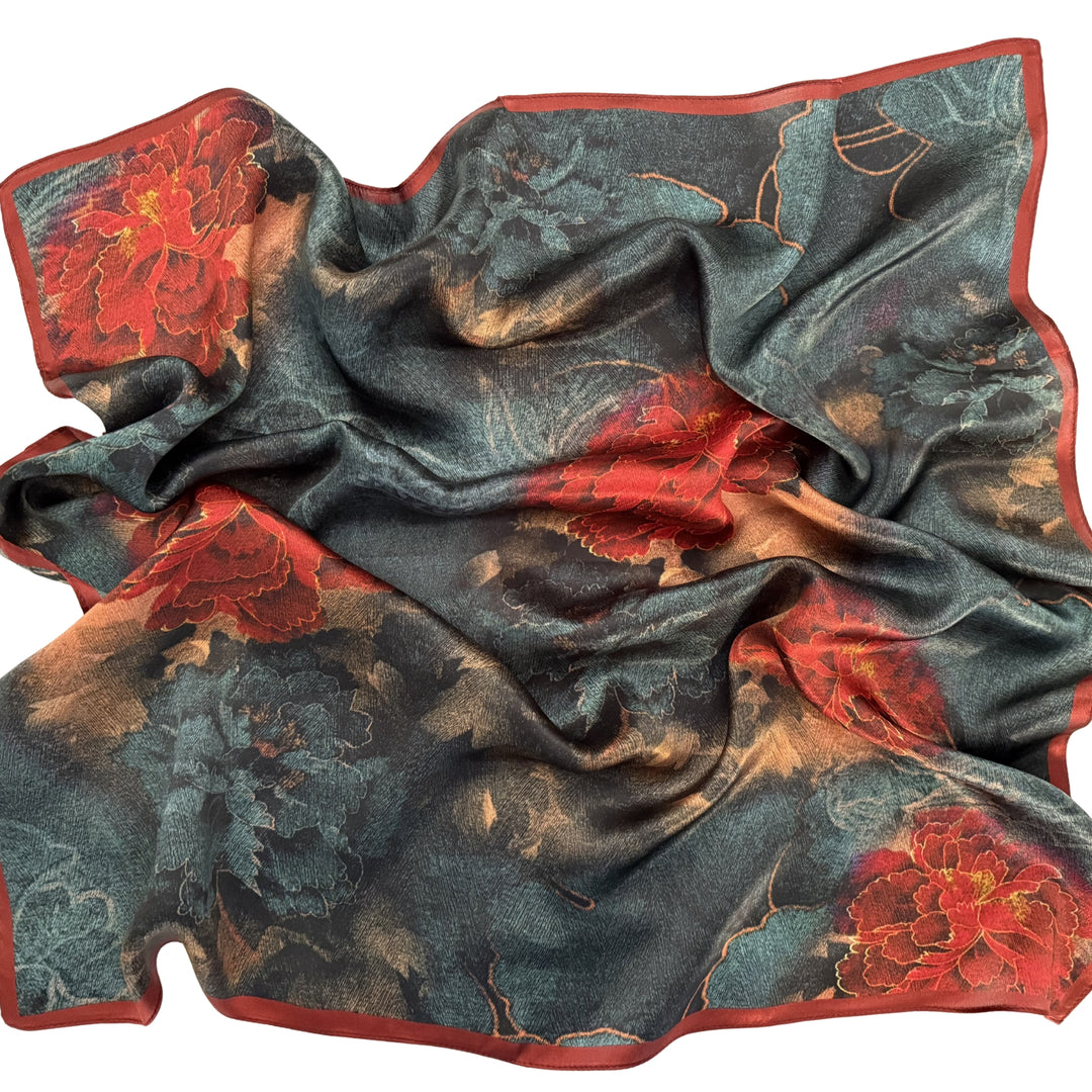 Red and blue floral silk scarf softly laid out in a relaxed arrangement.