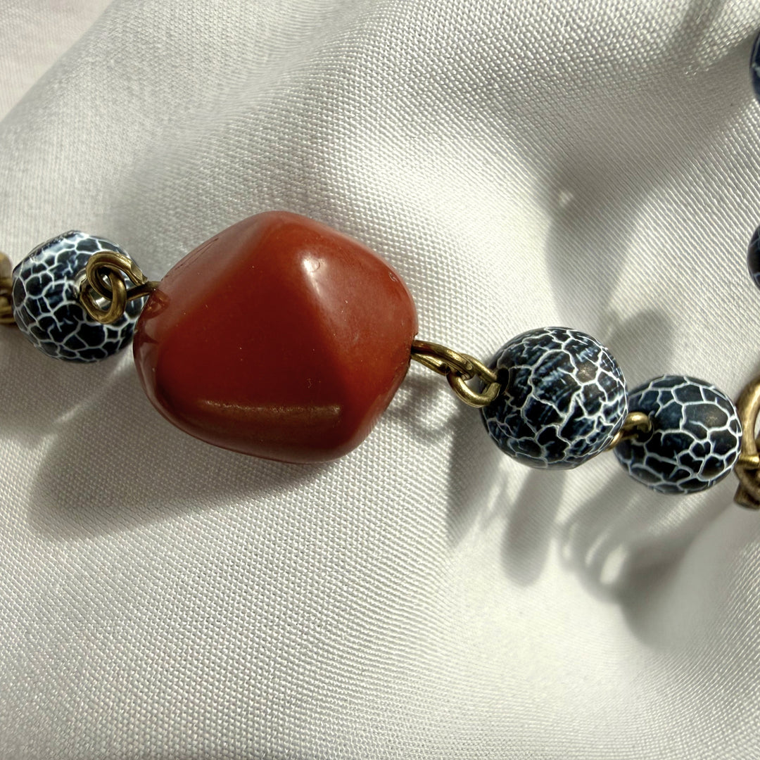 Angled close-up of red jasper stones and crackle agate in a handcrafted wooden pendant necklace.