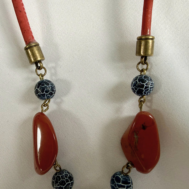 Close-up of red jasper, crackle agate, and cord fitting detail on a handcrafted pendant necklace.