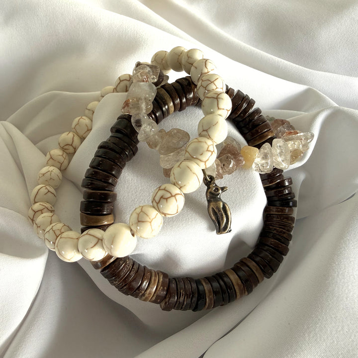 Full view of three handcrafted beaded bracelets layered together with howlite, coconut wood, and mother of pearl beads.