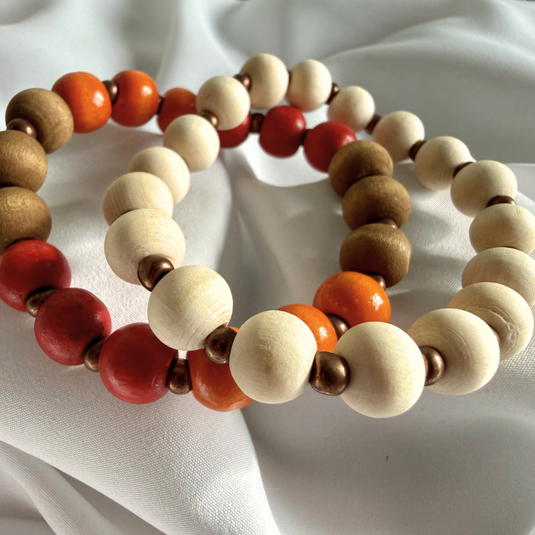 Full view of two handcrafted beaded bracelets in warm earth tones featuring wood beads and golden seed bead accents.