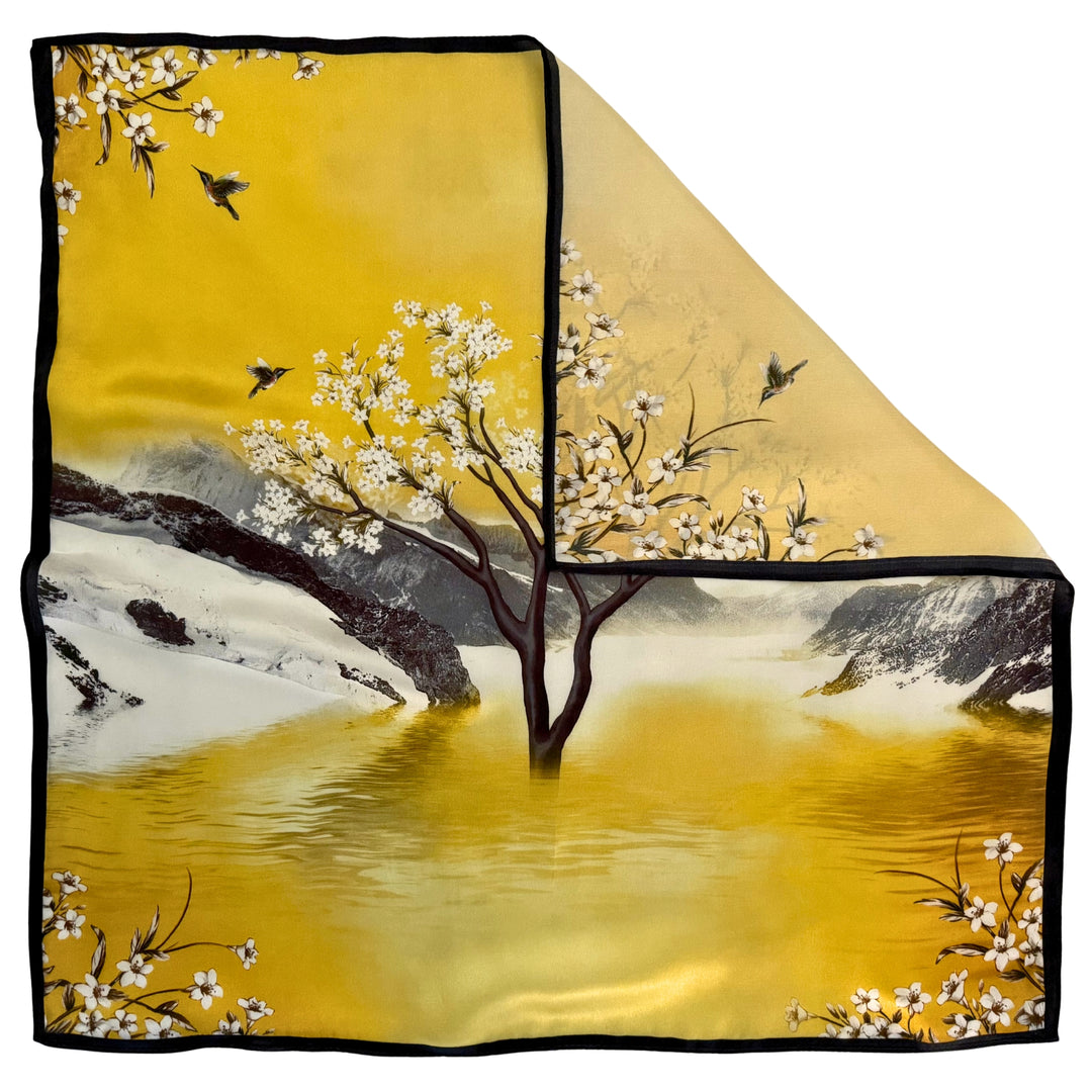 Top view of a silk scarf with one corner folded to show the reverse side and the difference in color due to the one-sided landscape print.