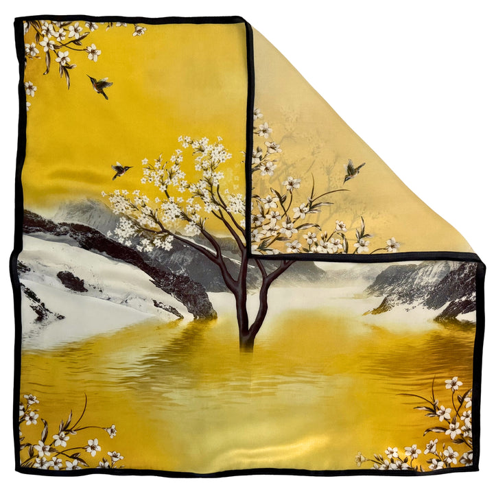 Top view of a silk scarf with one corner folded to show the reverse side and the difference in color due to the one-sided landscape print.