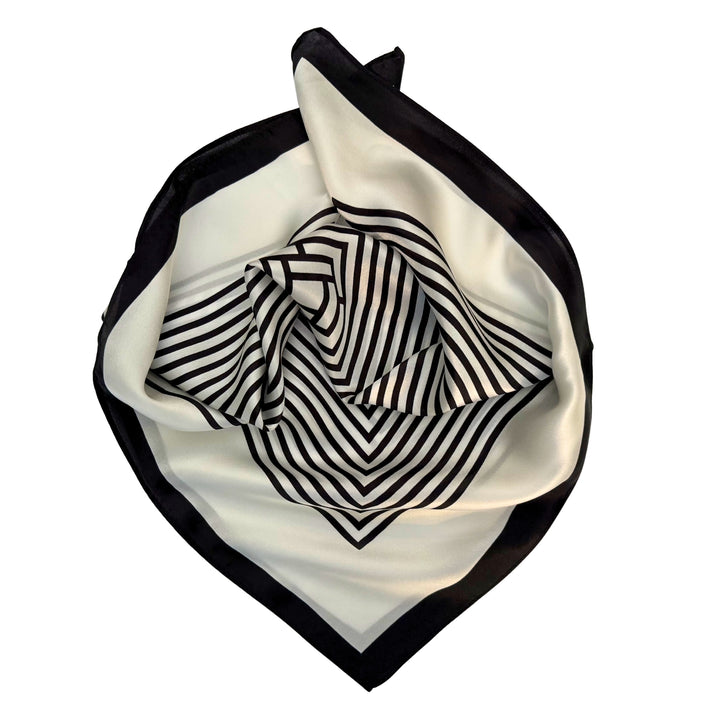 Partially folded silk scarf highlighting the smooth silk texture and subtle black and ivory labyrinth design.