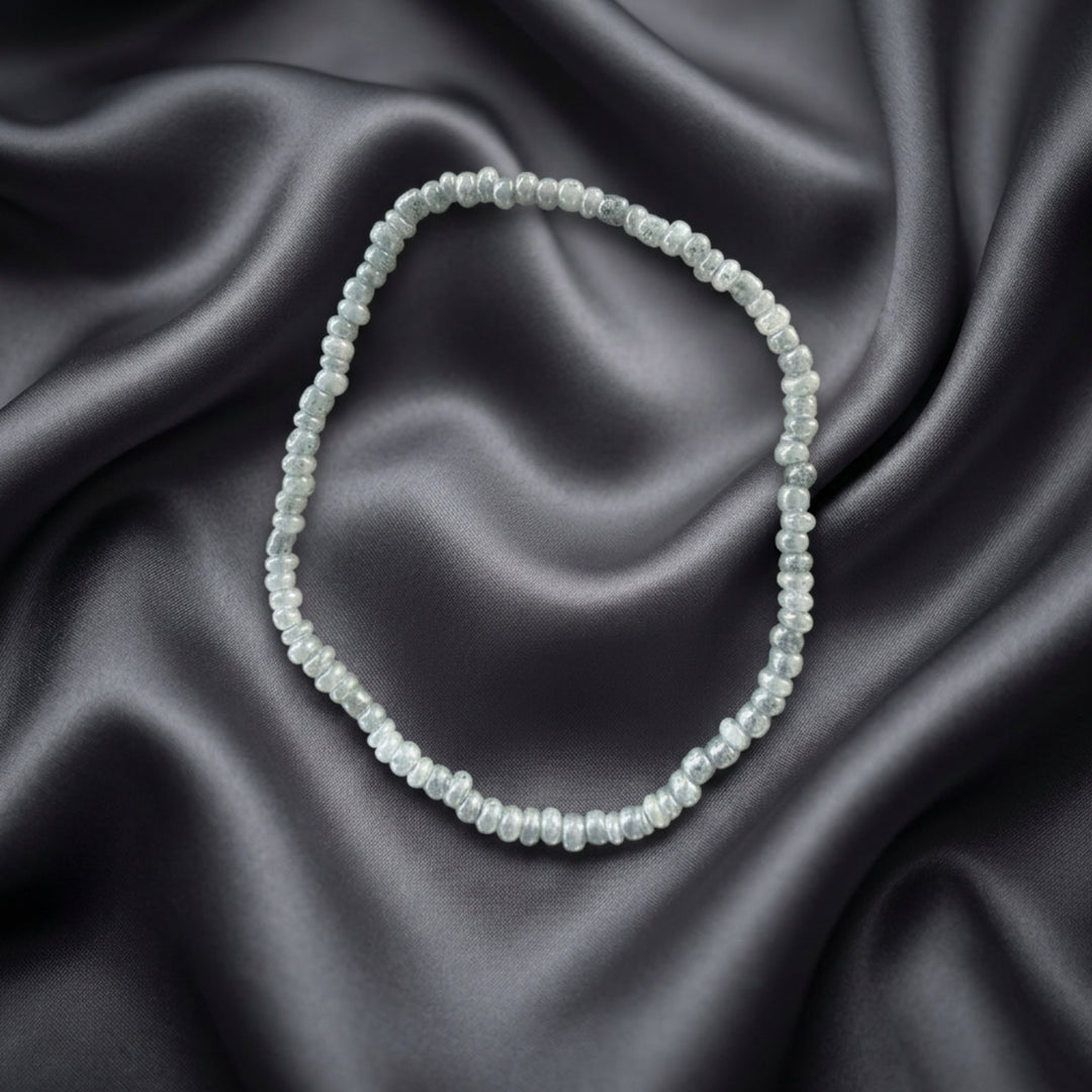 Full view of a handcrafted bracelet made with small silver-tone beads on elastic cord.