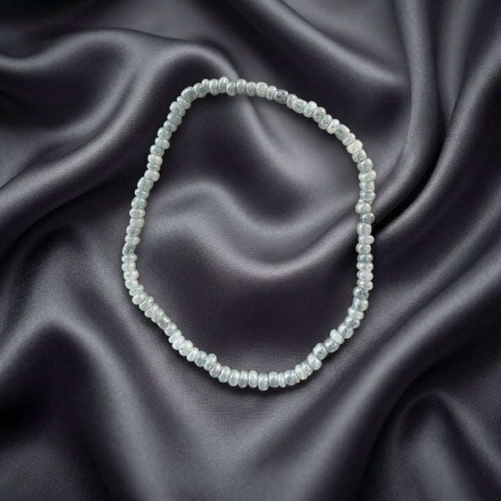 Full view of a handcrafted bracelet made with small silver-tone beads on elastic cord.