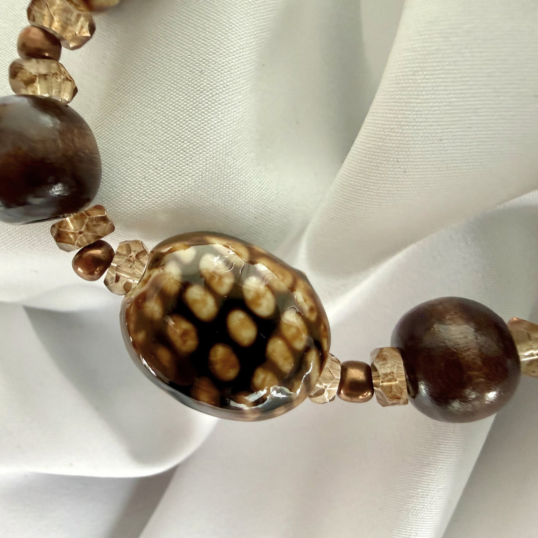 Close-up of patterned ceramic beads paired with wood and glass beads on an elastic bracelet.